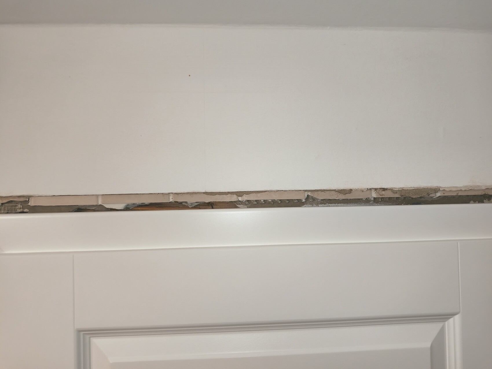 Wand mit abplatzendem Putz über dem Türrahmen, deutlich sichtbare Baumängel
