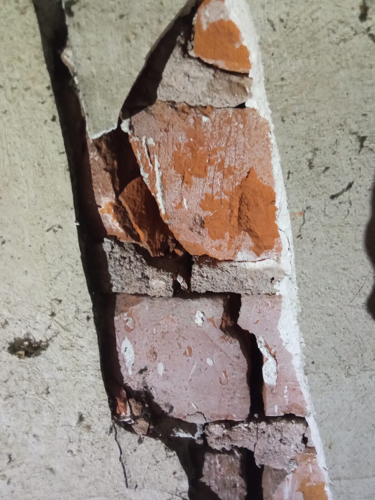 Nahaufnahme einer bröckelnden Ziegelmauer mit roten Ziegelsteinen und bröckeligem Mörtel.