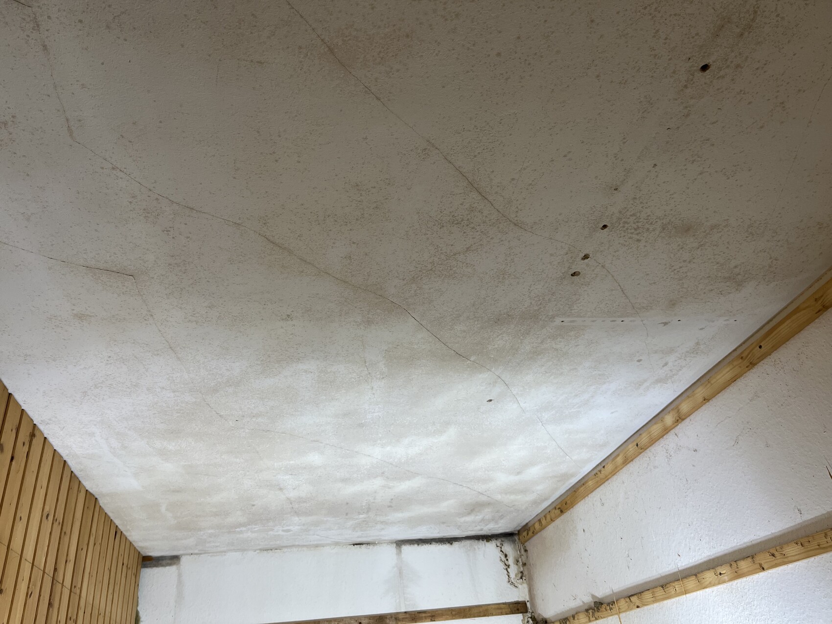 Rohbau-Decke mit Rissen und Holzverkleidung an den Wänden im Innenraum