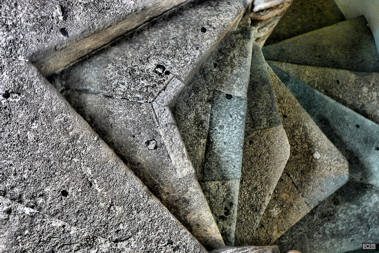 Spiralförmige Betontreppe mit rauer, staubiger Oberfläche in grauem Steinlook.
