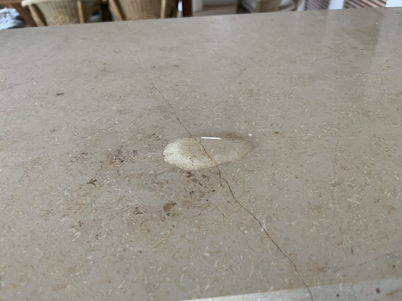 Auf einer beigen Steinplatte liegt ein kleines weißes Steinchen; eine Risslinie zieht darüber.