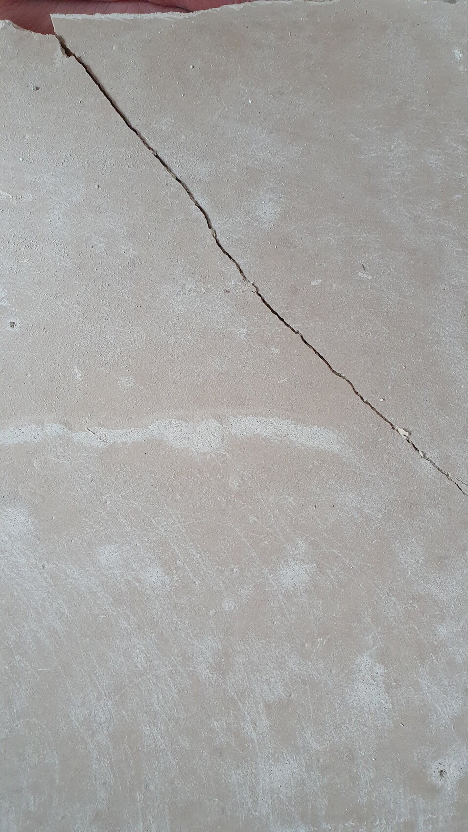 Betonboden mit einer diagonalen Rissspur von oben links nach unten rechts.