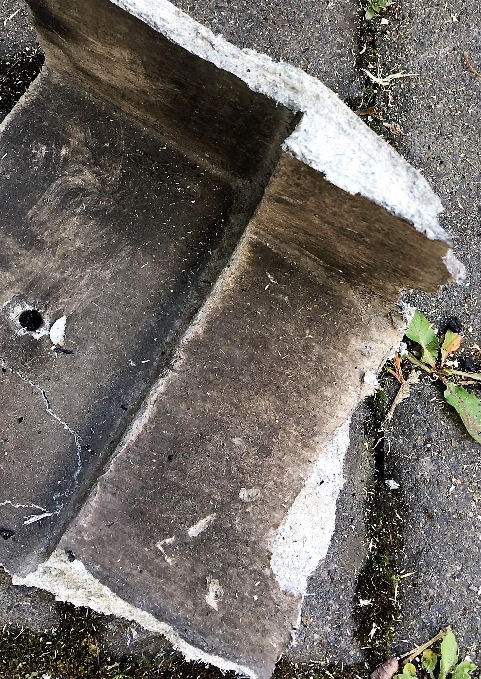 Bruchstück eines Betonfundaments mit rauer Oberfläche auf Asphalt