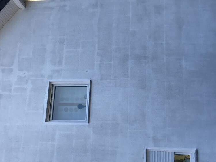 Außenansicht einer Betonfassade mit zwei quadratischen Fenstern