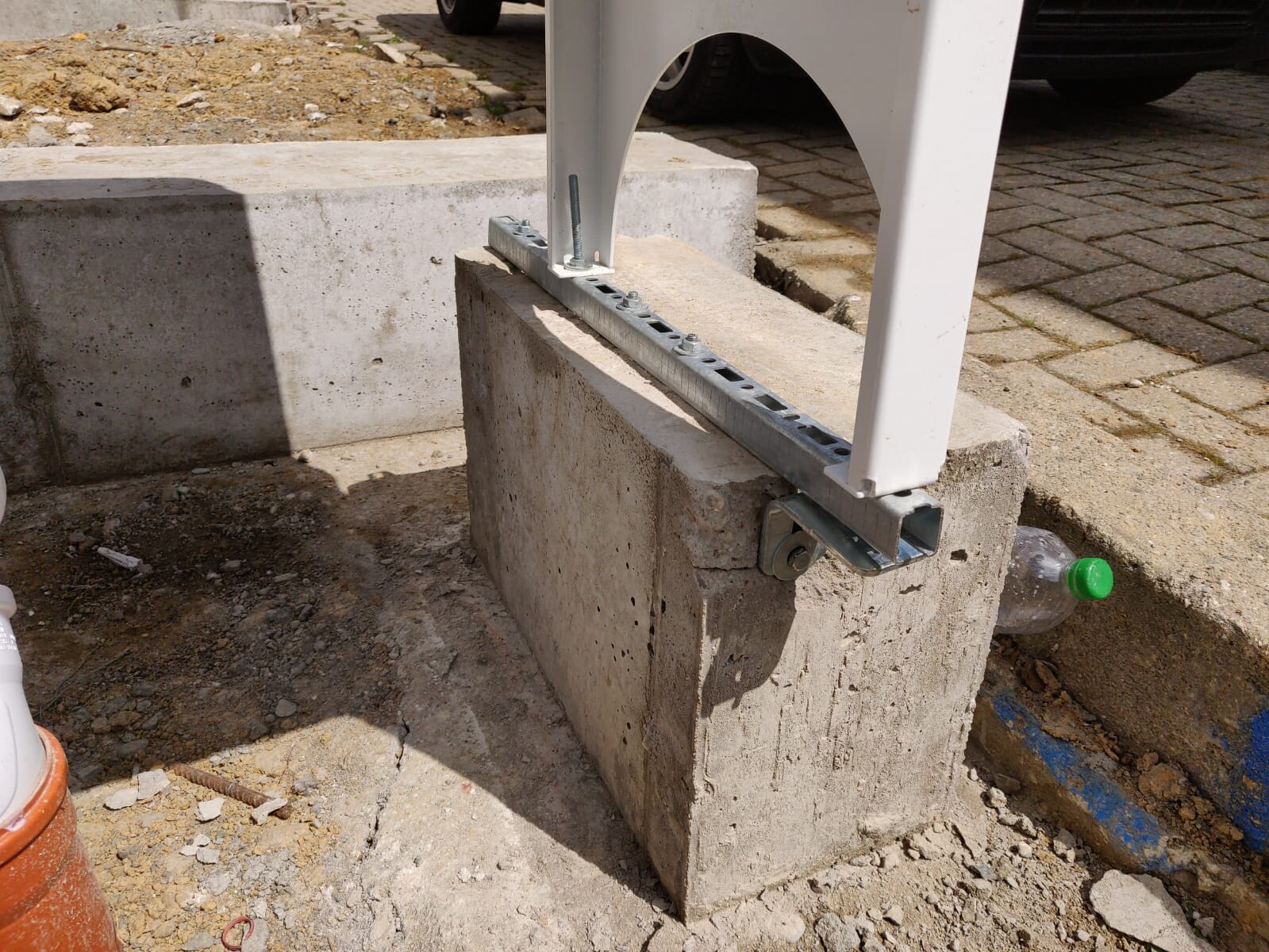 Baustelle: Betonfundament mit Metallankerträger und weißer Stütze.