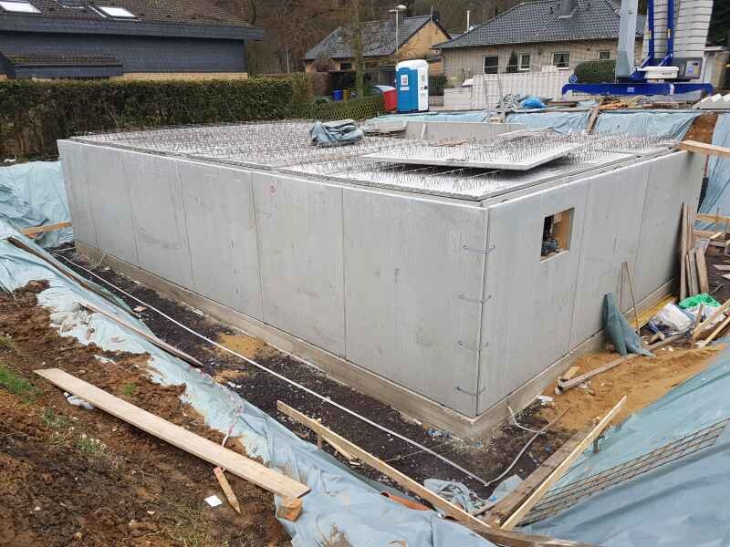 Großes Betonfundament auf Baustelle mit Bewehrungsstahl auf der Oberseite und Bauzubehör.
