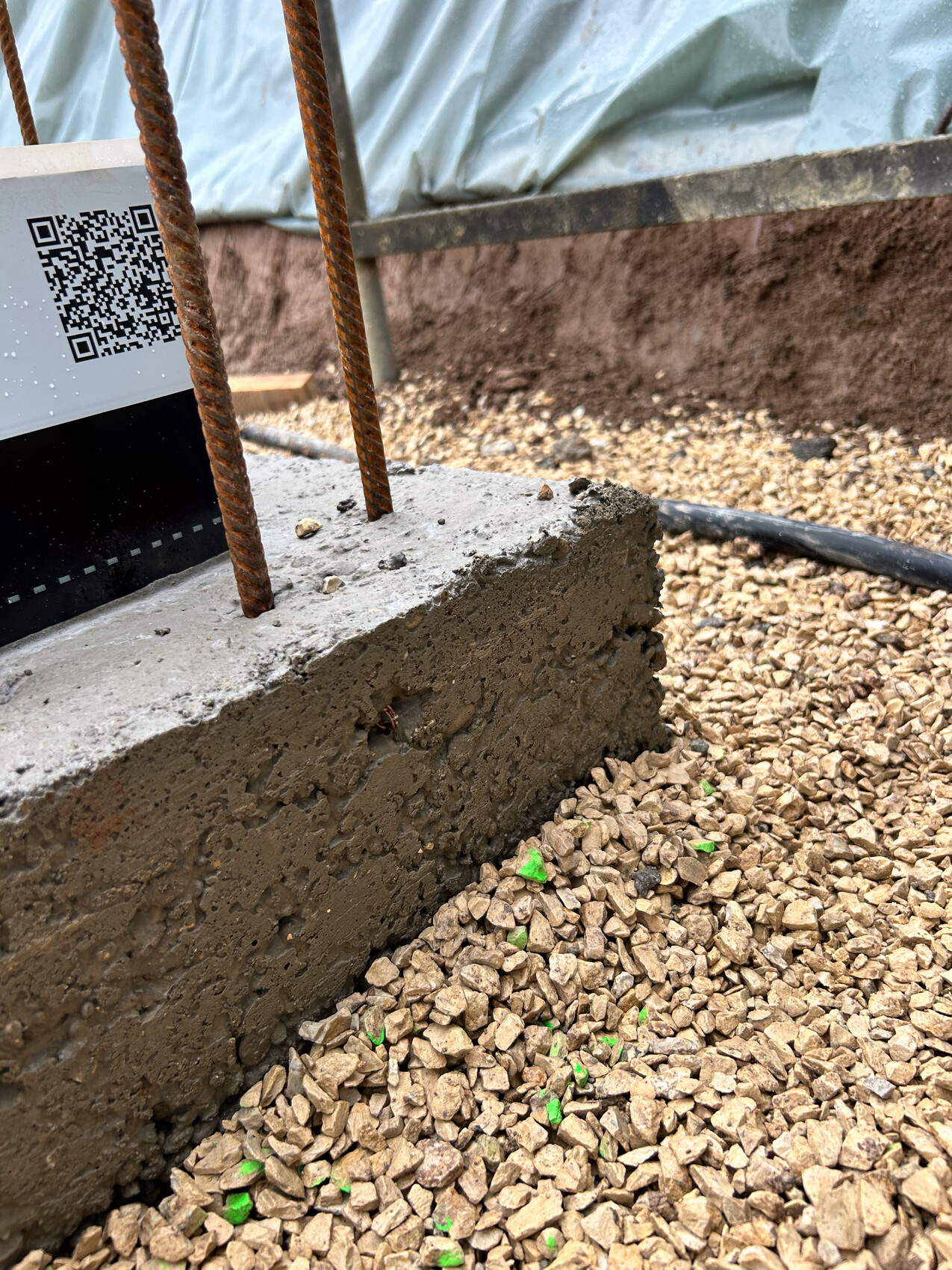 Betonfundament mit Stahlbewehrung auf Kiesboden einer Baustelle