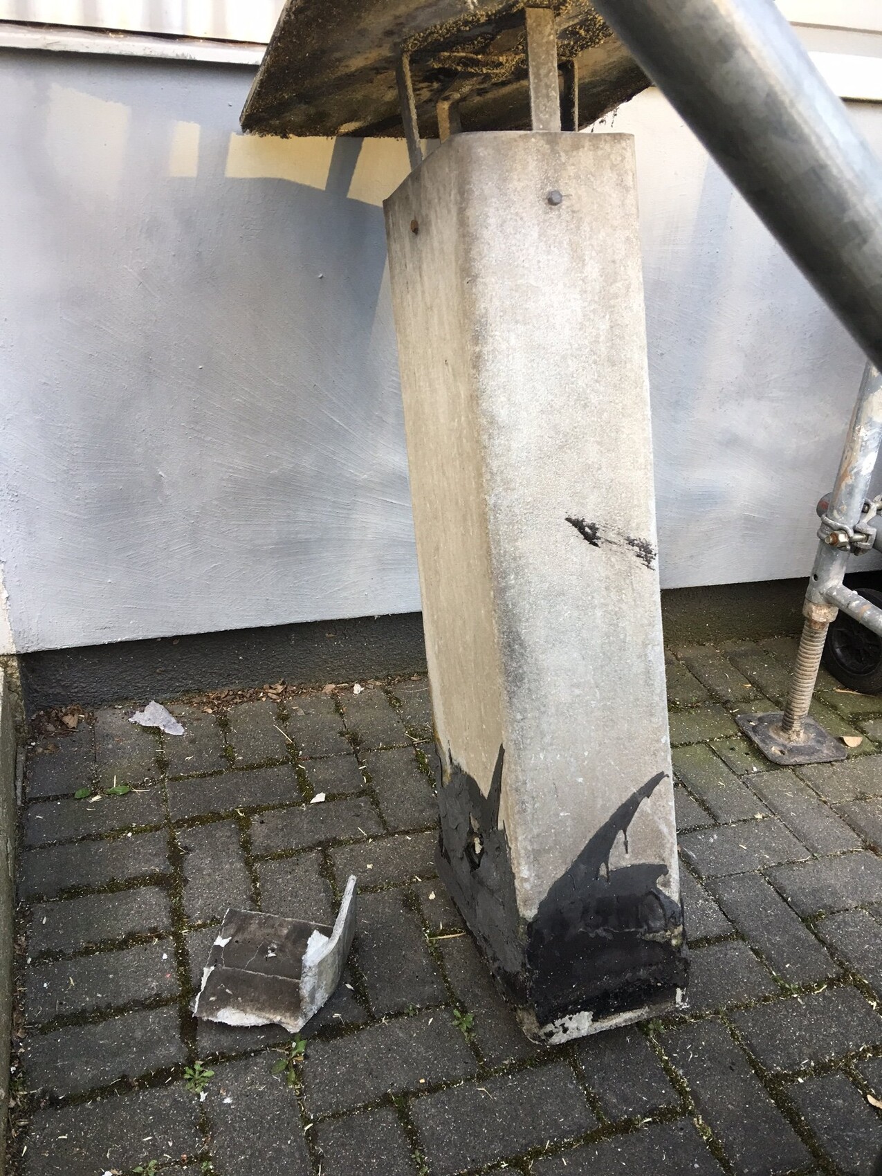 Betonfundament im Außenbereich mit Beschädigung, Bruchstücken und Gerüst im Hintergrund
