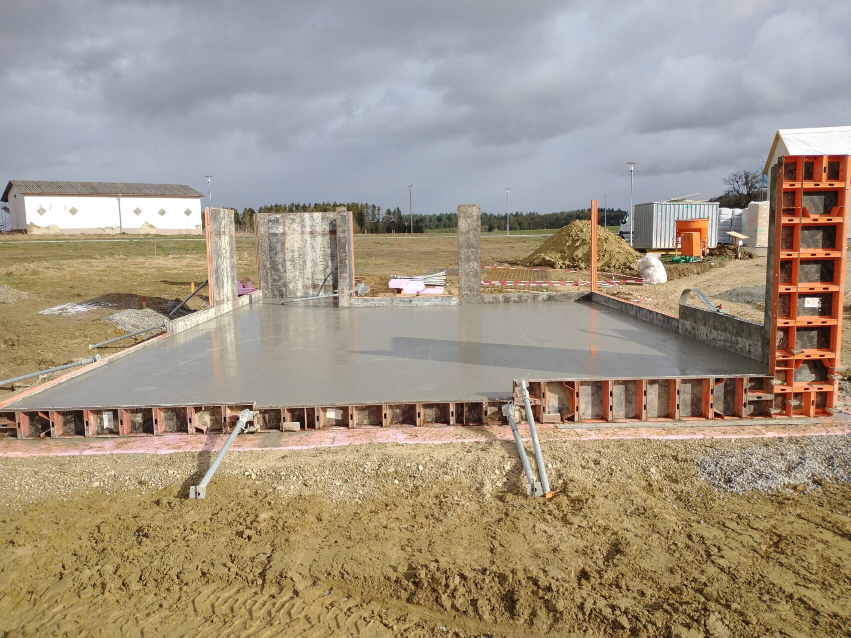 Frisch gegossene Betonfundamentplatte auf einer Baustelle mit Formarbeiten.