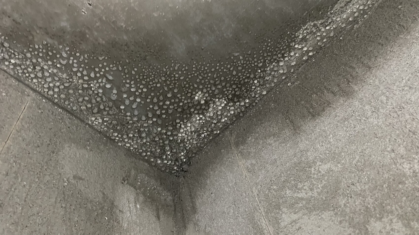 Feuchte Betonecke mit vielen kleinen Wassertropfen entlang der Kante.
