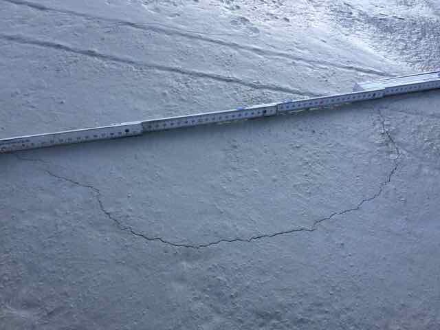Betonoberflaeche mit Riss und Messband