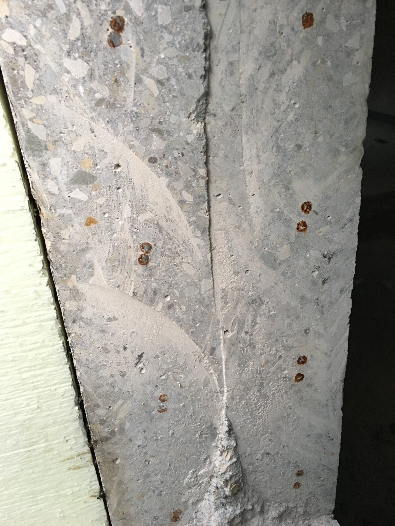 Nahaufnahme von rauem Beton mit Rostflecken an Bewehrung