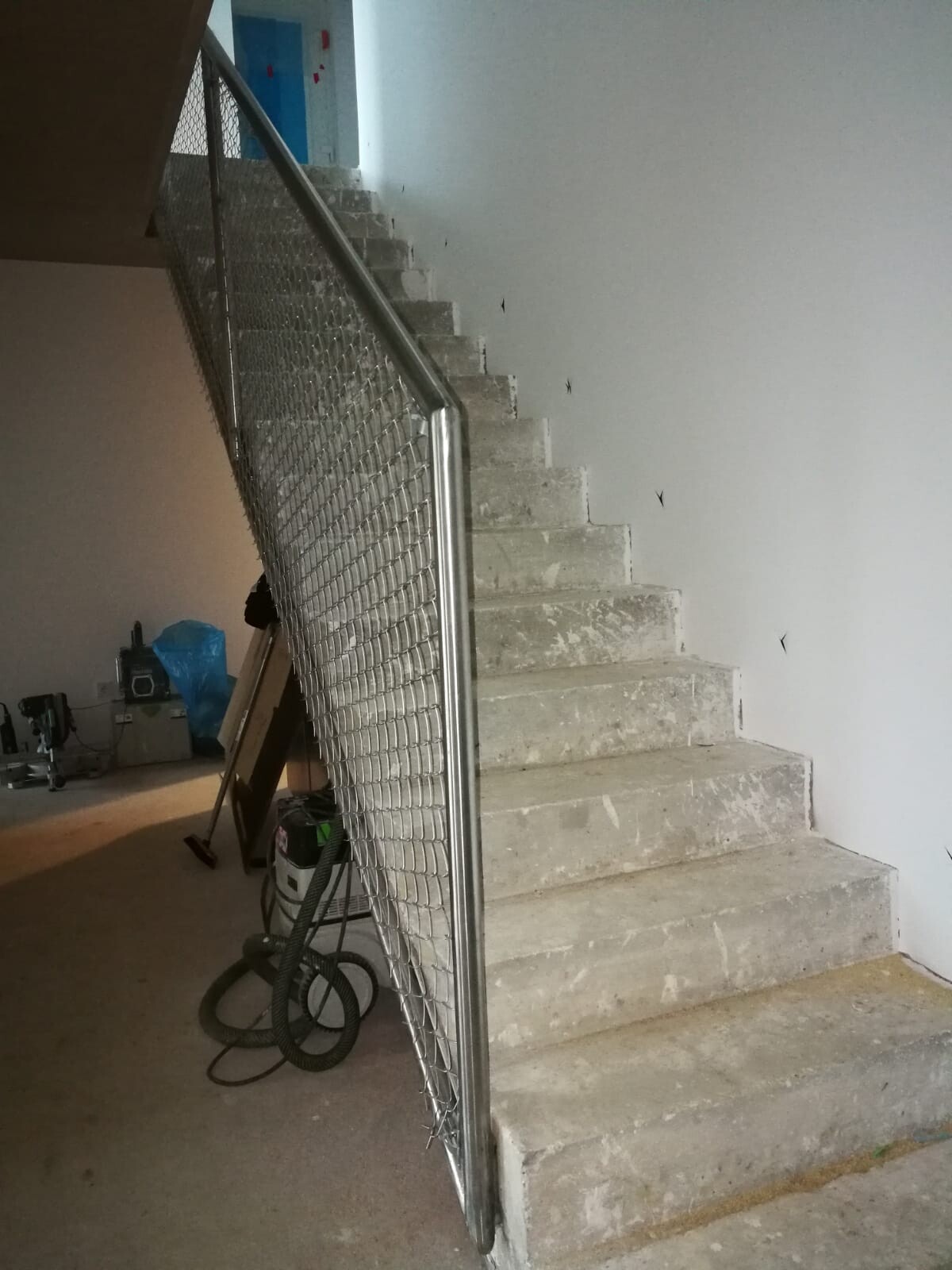 Betontreppe mit Metallgittergeländer in einem Bauprojekt; Werkzeuge unten links.