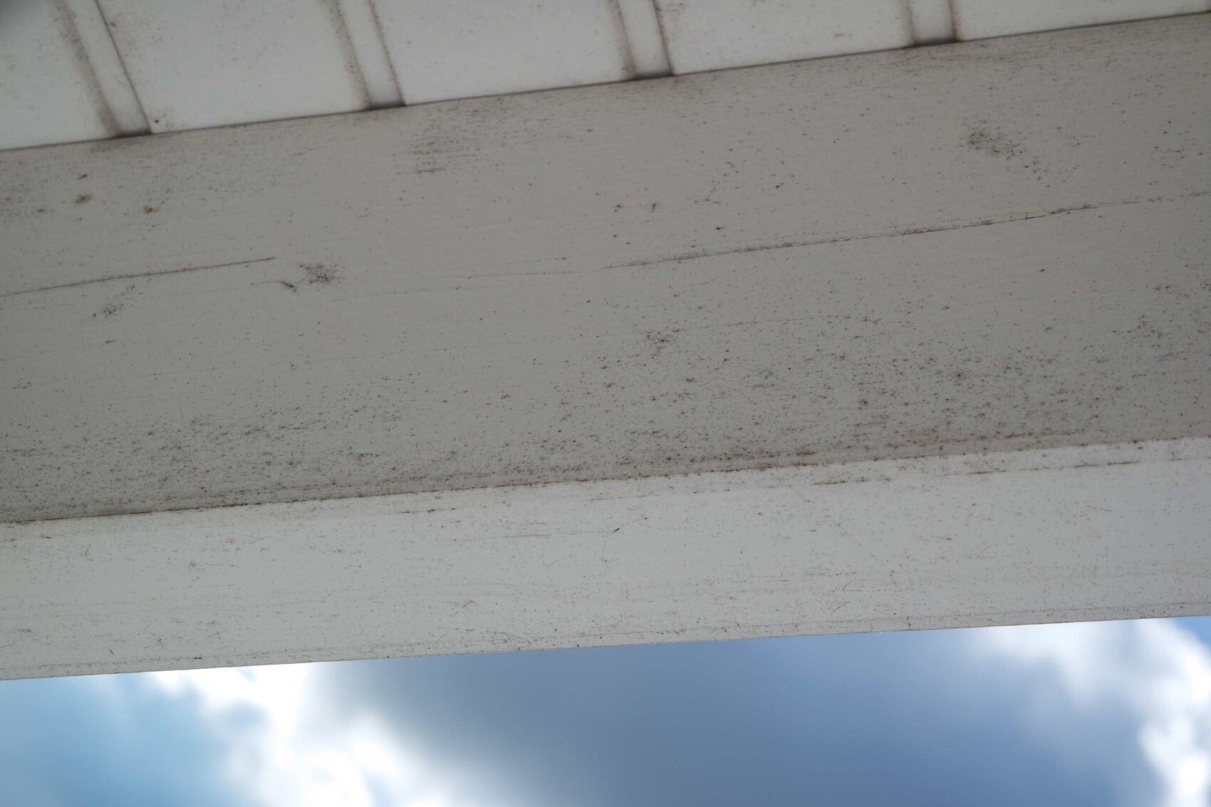 Unterseite eines Betonbauteils mit Staubflecken, Himmel im Hintergrund