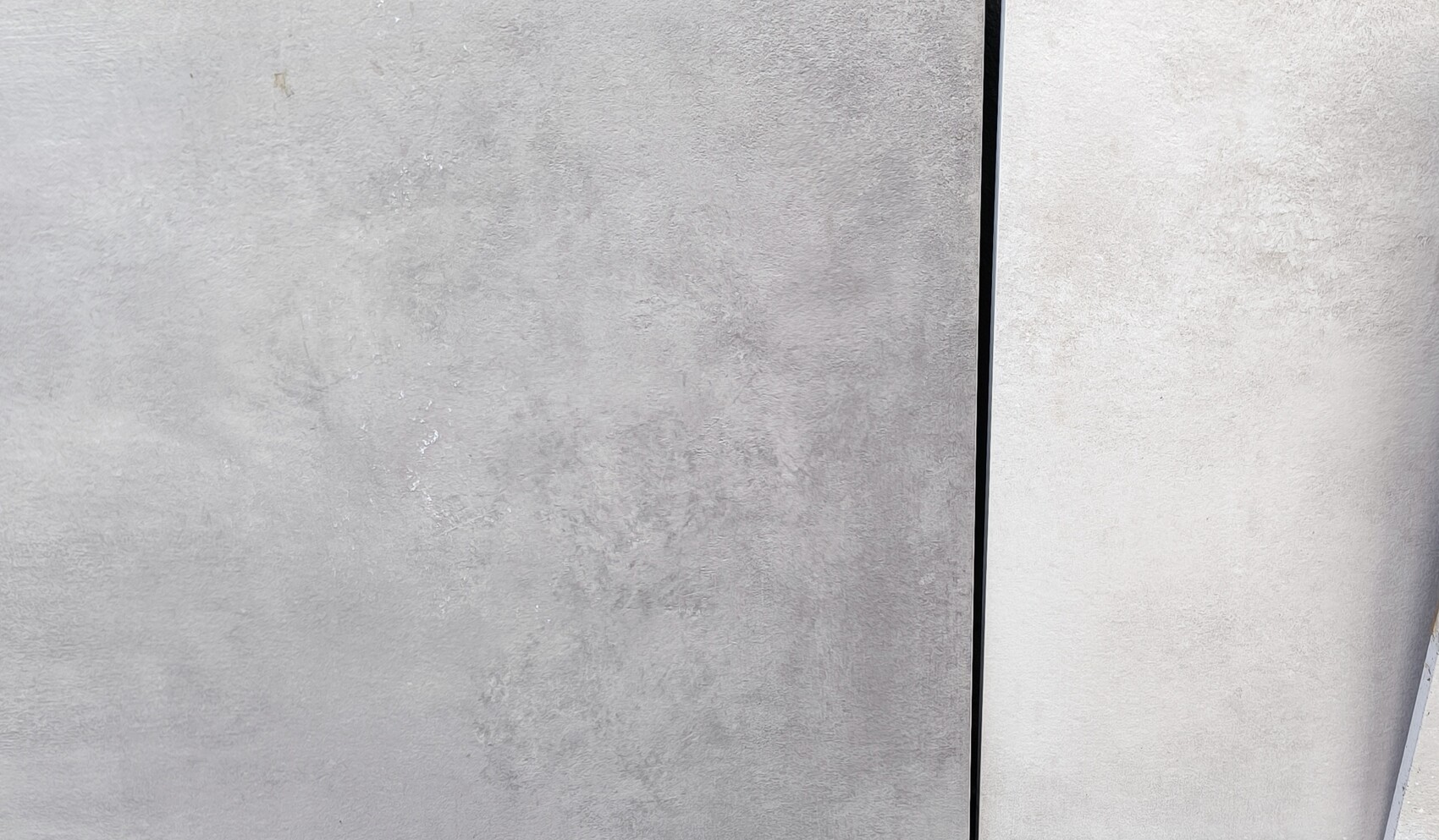 Grobe Nahaufnahme einer grauen Betonwand mit senkrechter Fuge und Oberflächentextur