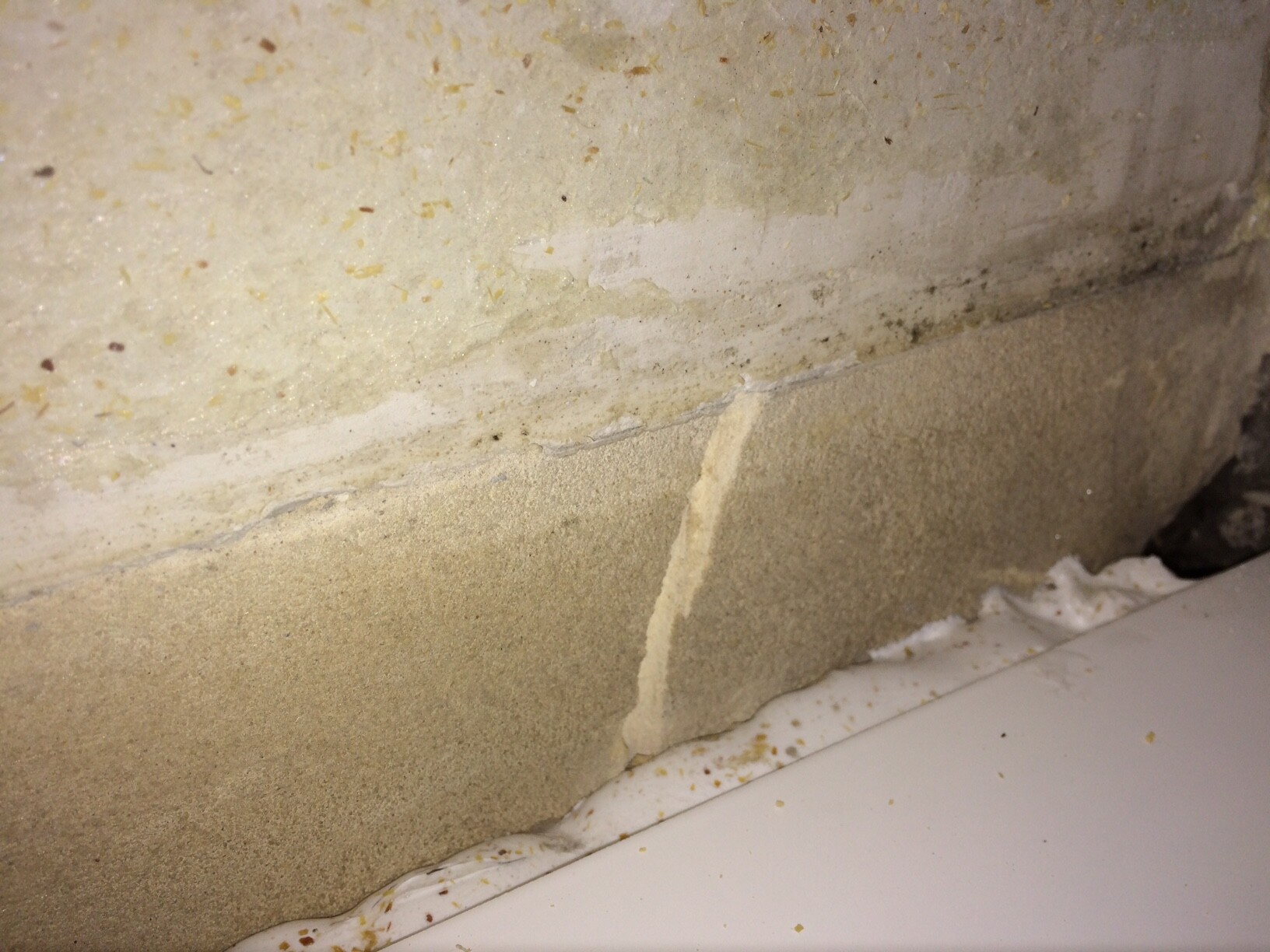 Riss in Betonwand am Fundamentbereich neben Fliesenboden.