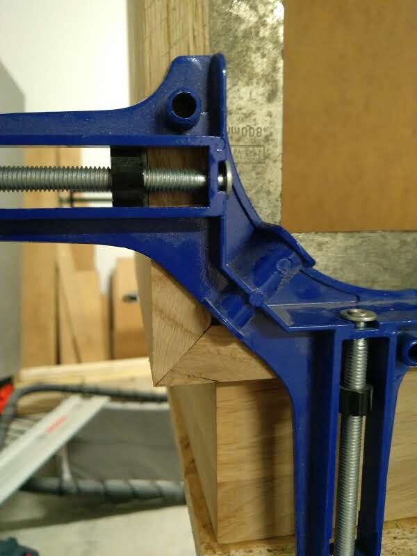 Blaue Schraubzwinge klemmt zwei Holzstücke in der Werkstatt.