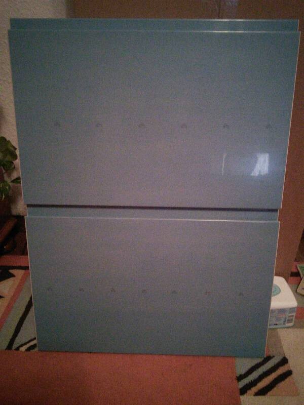 Zwei blaue Schrankfronten stehen übereinander in einem Zimmer.