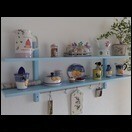Blaue Wandregale mit Geschirr, Vasen und Deko-Objekten an einer Wohnzimmerwand.