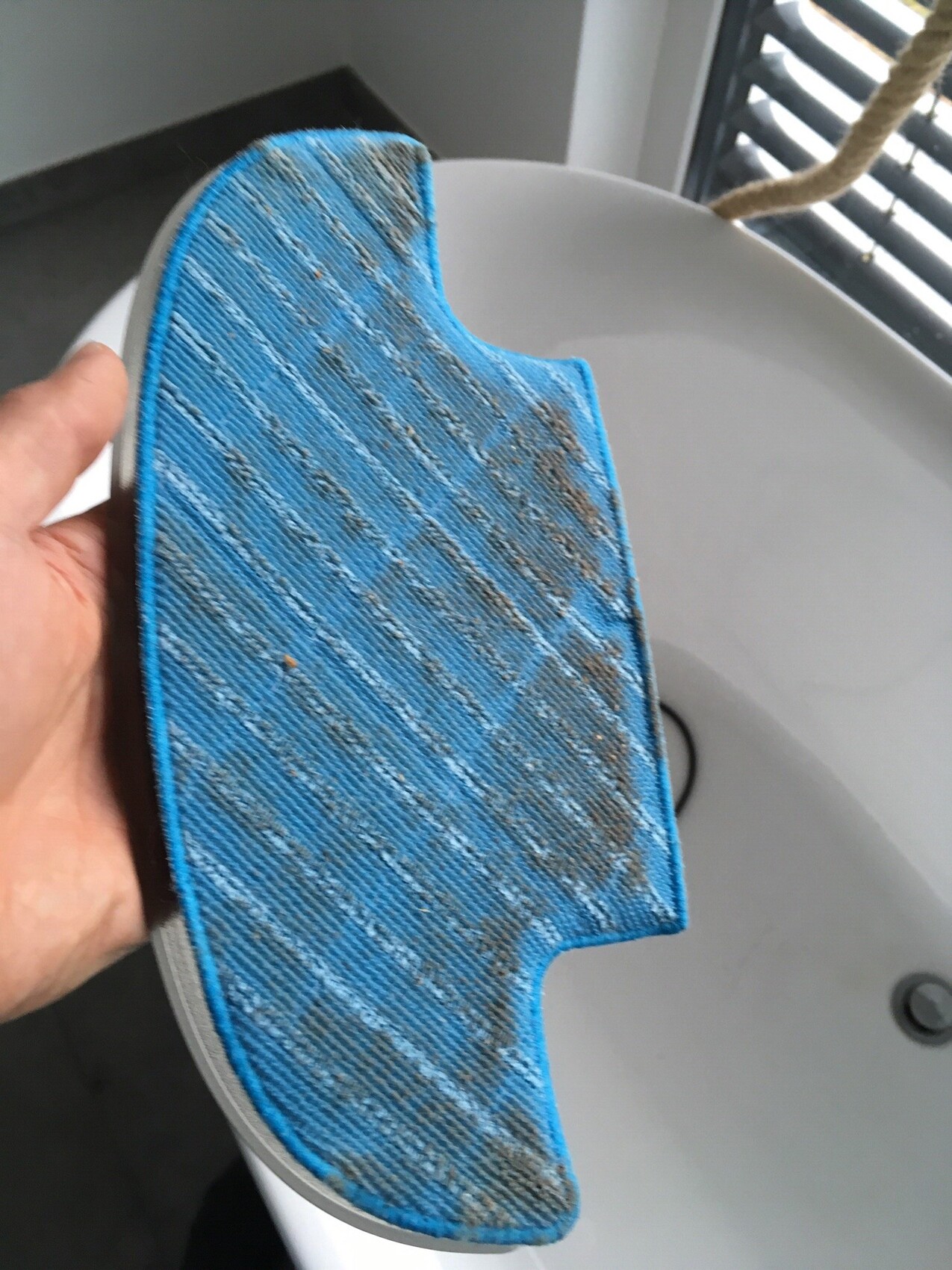 Blauer Mikrofaser-Reinigungspad mit Schmutz am Waschbeckenrand
