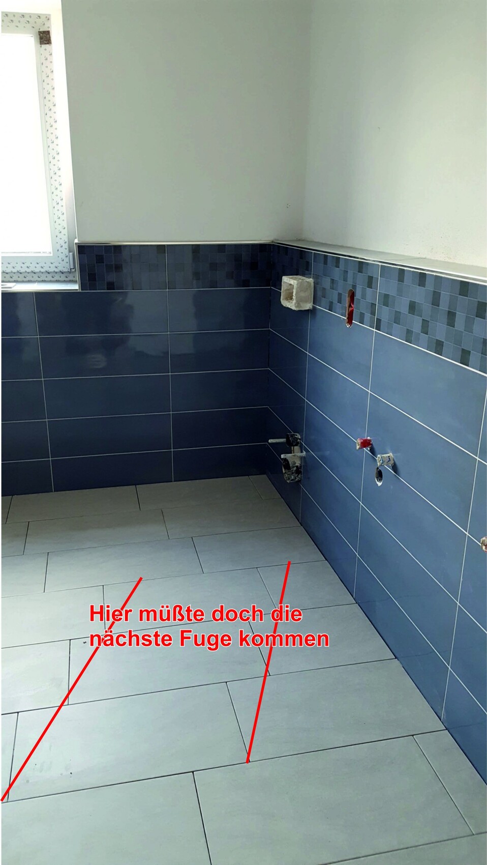 Badezimmer-Baustelle: dunkle Wandfliesen, helle Bodenfliesen; rote Linien zeigen fehlende Fuge.