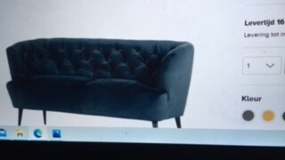 Blaues, gepolstertes Sofa mit Knopfsteppung vor hellem Hintergrund
