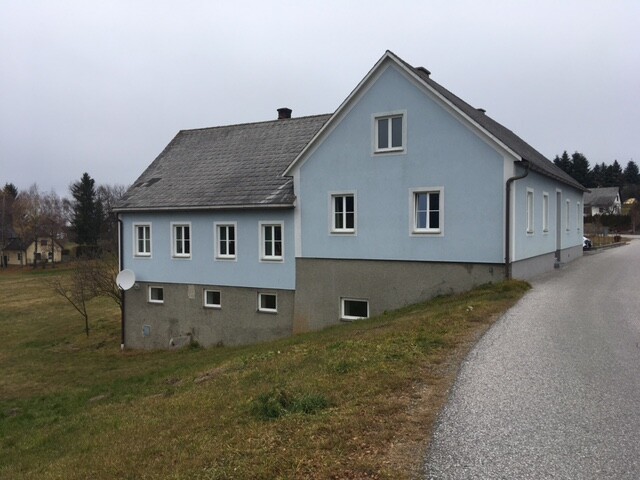 Außenansicht eines blauen Hauses am Hang neben einer Straße