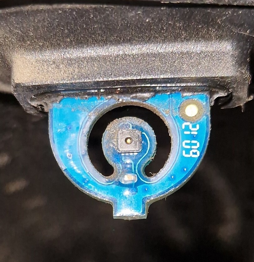 Kleiner blauer runder Sensor-Slot mit zentralem Quadratbauteil in dunkler Umgebung.