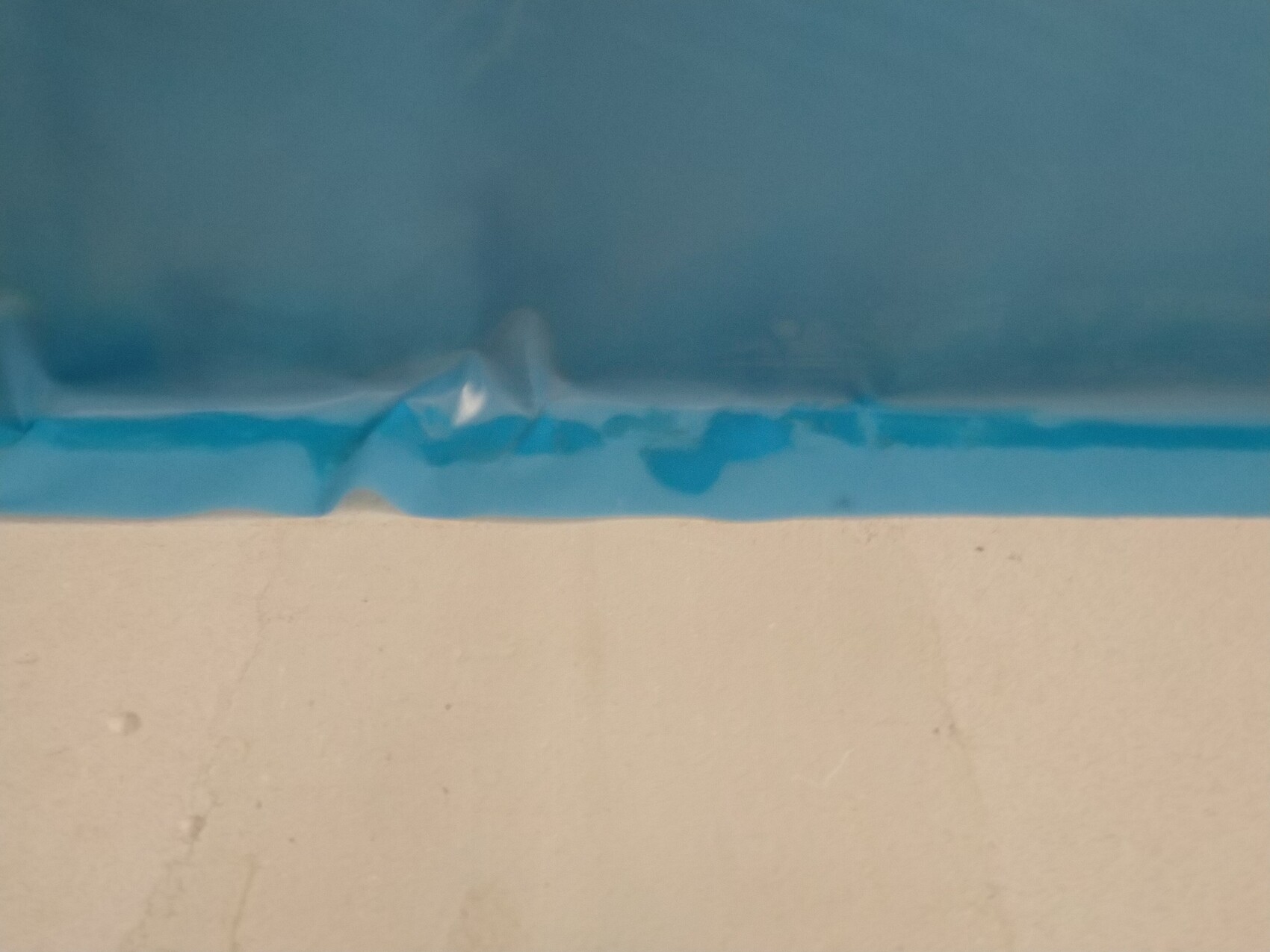 Nahaufnahme eines blauen Malerbands an einer weißen Wand während Bauarbeiten
