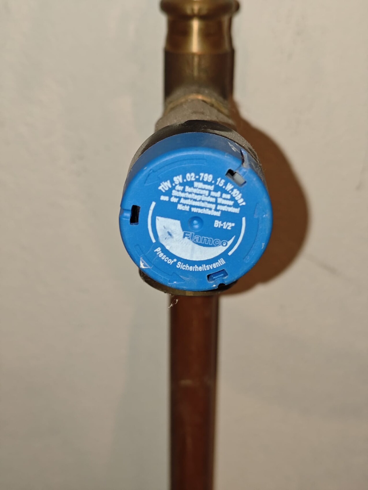 Blaue Sicherheitsventilkappe am Kupferrohr einer Wasserleitung, Installationsanschluss sichtbar
