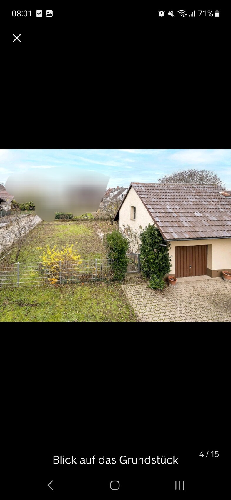 Vorderansicht eines Einfamilienhauses mit braunem Ziegeldach, Hof und Gartenzaun.