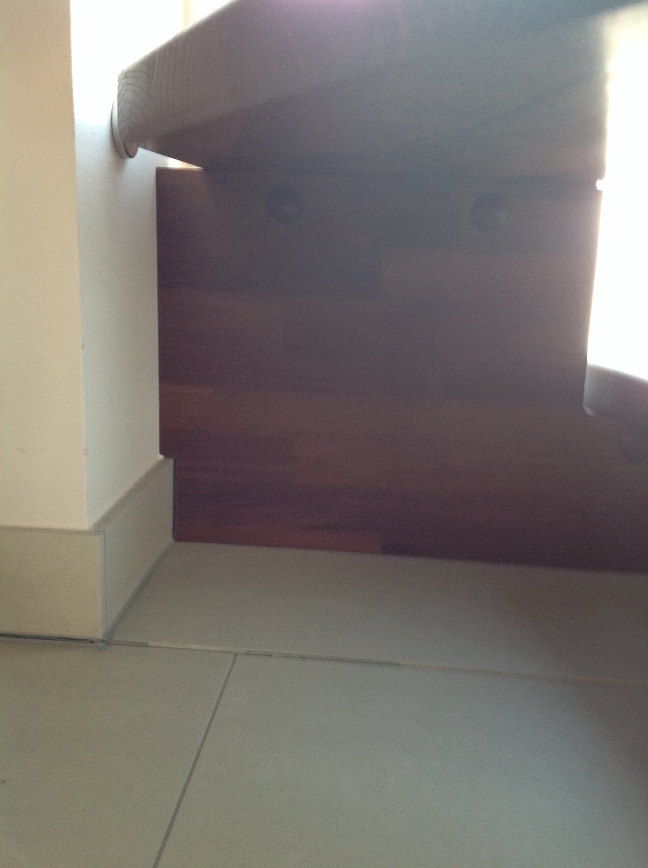 Innenraum mit grauen Fliesenboden und braunem Holzpaneel an der Wand