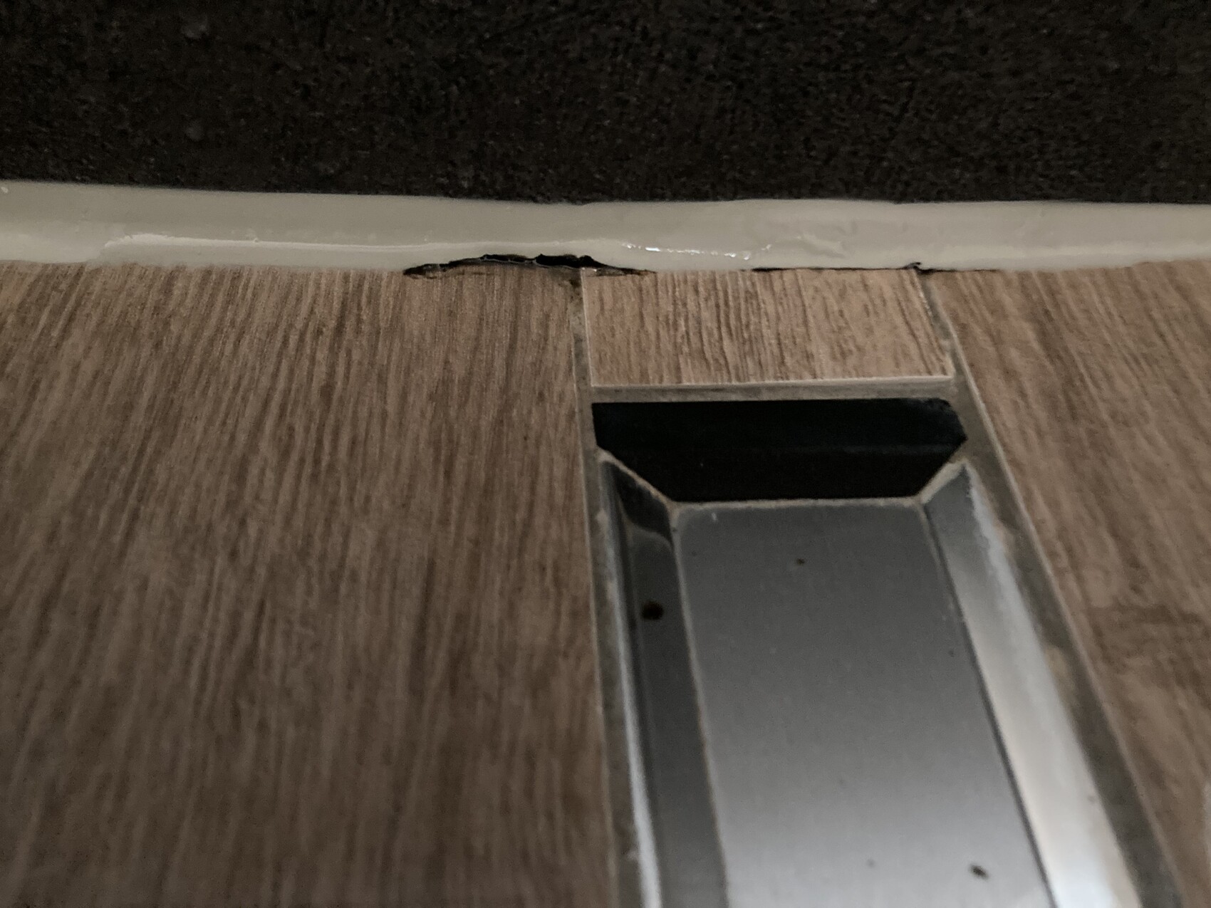 Holzoptik Bodenbelag mit Metall-Schwelle und beschädigter Fuge