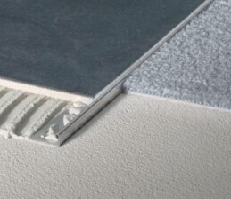 Nahaufnahme einer Bodenbelagskante mit Metallprofil und Unterlage