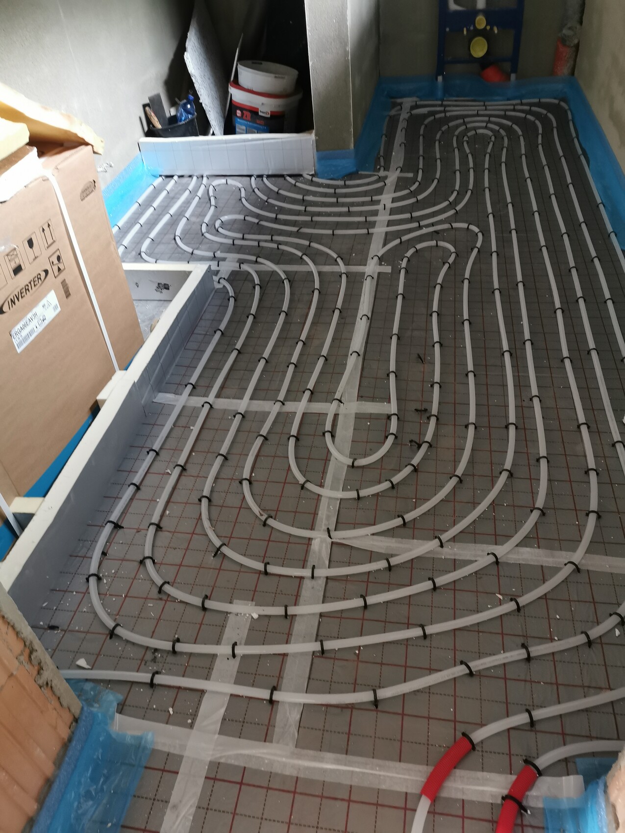 Fußbodenheizungsrohre liegen spiralförmig auf einer Dämmunterlage während der Bauphase.