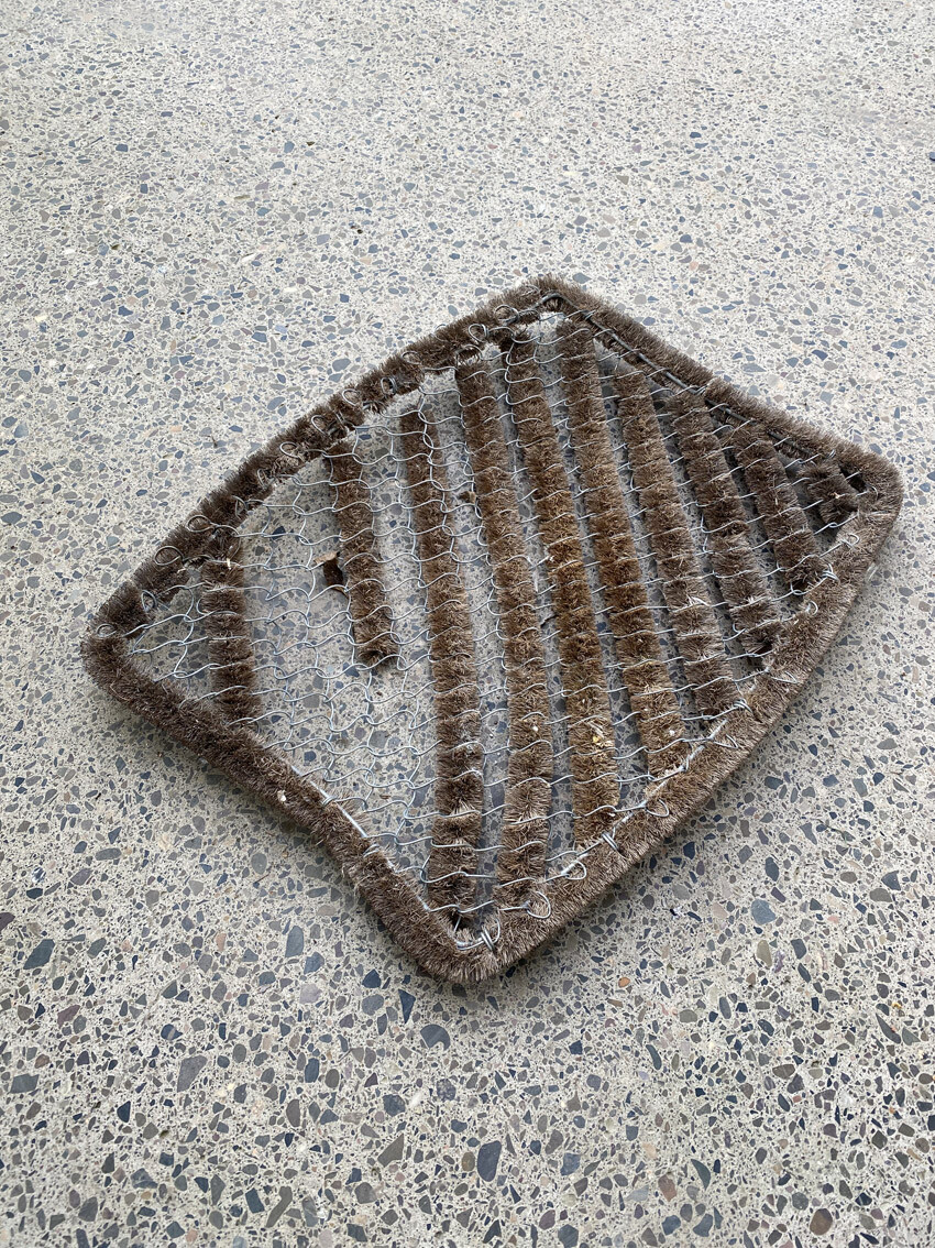 Bräunliche Eingangsmatte mit Metallgitter liegt auf terrazzo-boden