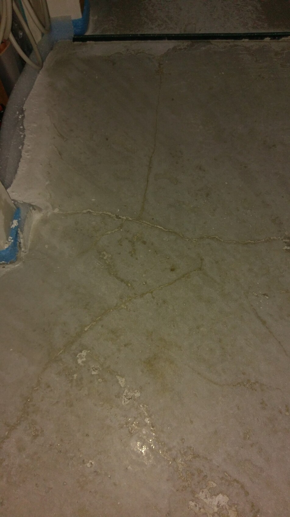 Bruechige Betonbodenplatte mit Rissen und Feuchtigkeitsspuren im Keller