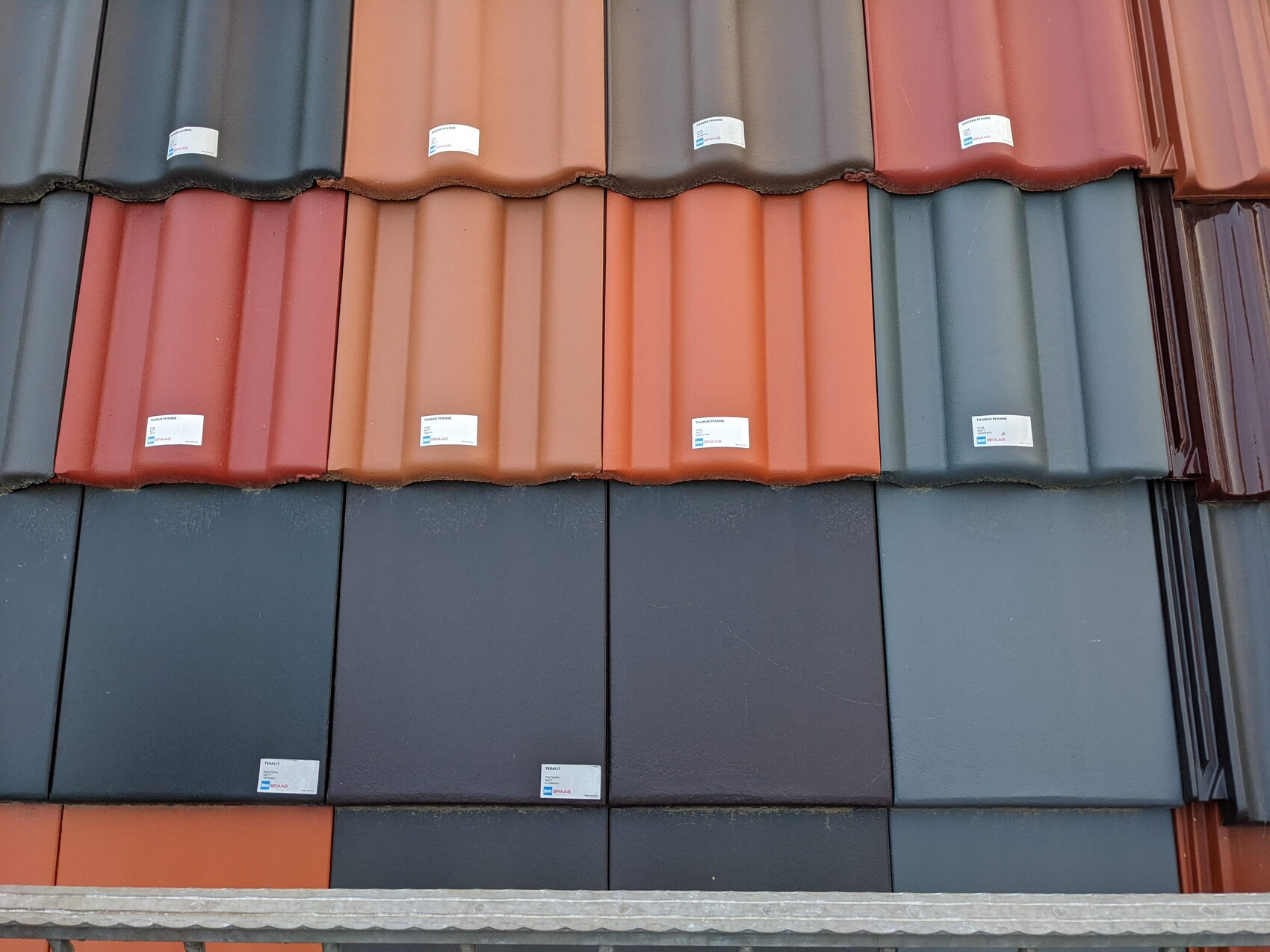 Bunte Dachziegel in Stapeln: Rot, Orange, Blau-Grau mit Etiketten.