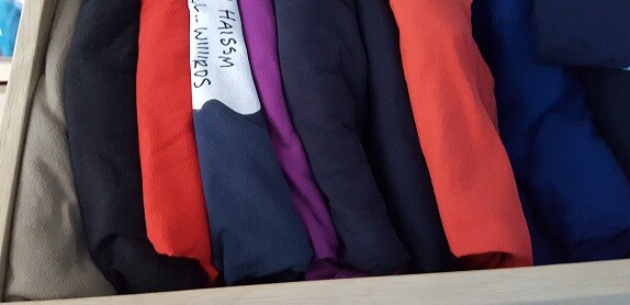 Bunte Stoffe in einer Reihe: Grau, Rot, Schwarz, Lila, Orange, Blau; Etikett sichtbar