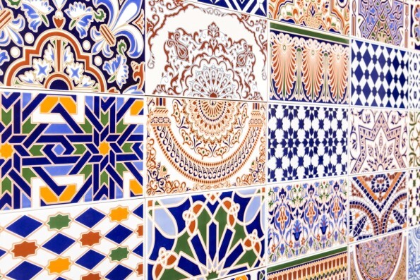 Bunte Fliesenwand mit geometrischen und floralen Mustern in Blau, Orange und Grün.