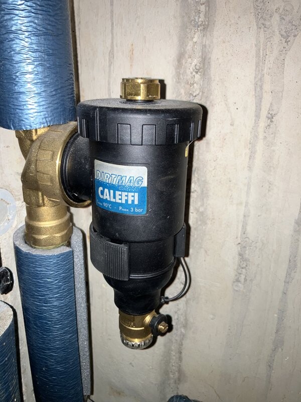 DirtMag-Filter von CALEFFI an Heizungsrohr, schwarzer Zylinder mit blauem CALEFFI-Schild.