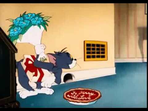 Tom der Kater hält Jerry die Maus im Wohnzimmer neben einer Blumenvase.