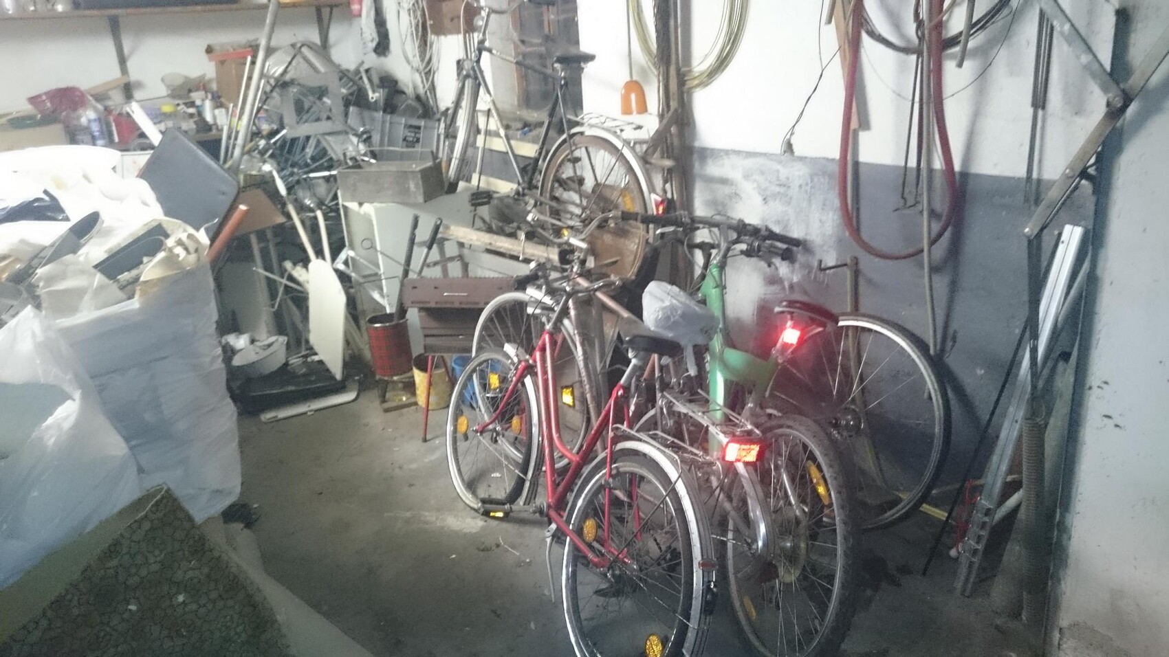 Chaotische Garage mit mehreren Fahrrädern, Werkzeugen und Lagergut.