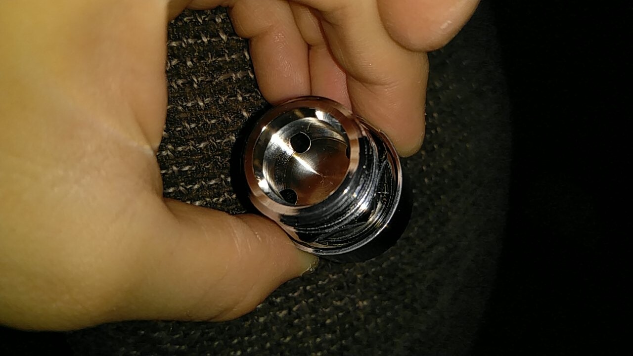 Nahaufnahme eines chromenen Ventilteils mit Gewinde, von Hand gehalten.