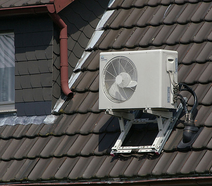 Außengerät einer Klimaanlage auf dem Ziegeldach, montiert auf Stahlhalterung.