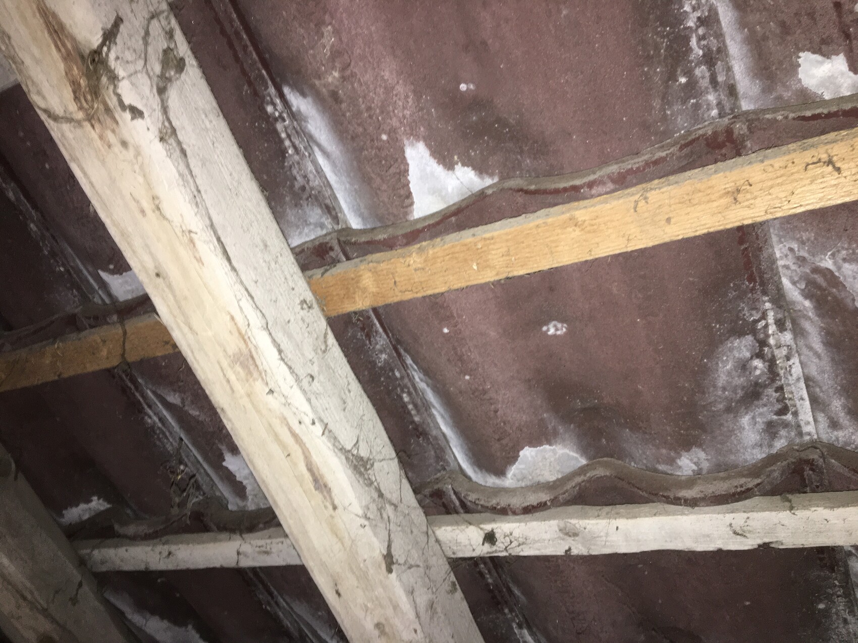 Dachboden mit Holz-Balken, Staub, Spinnweben und Tonziegeln.