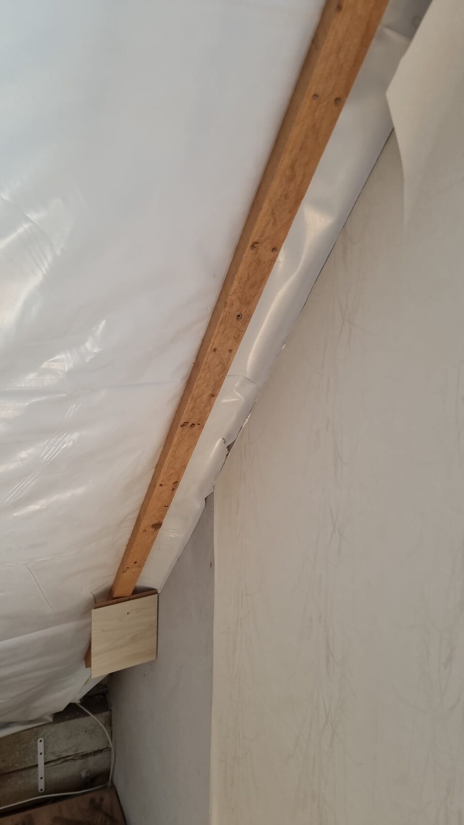 Dachboden mit Holzbalken, weißer Kunststoffabdichtung und Dachverkleidung