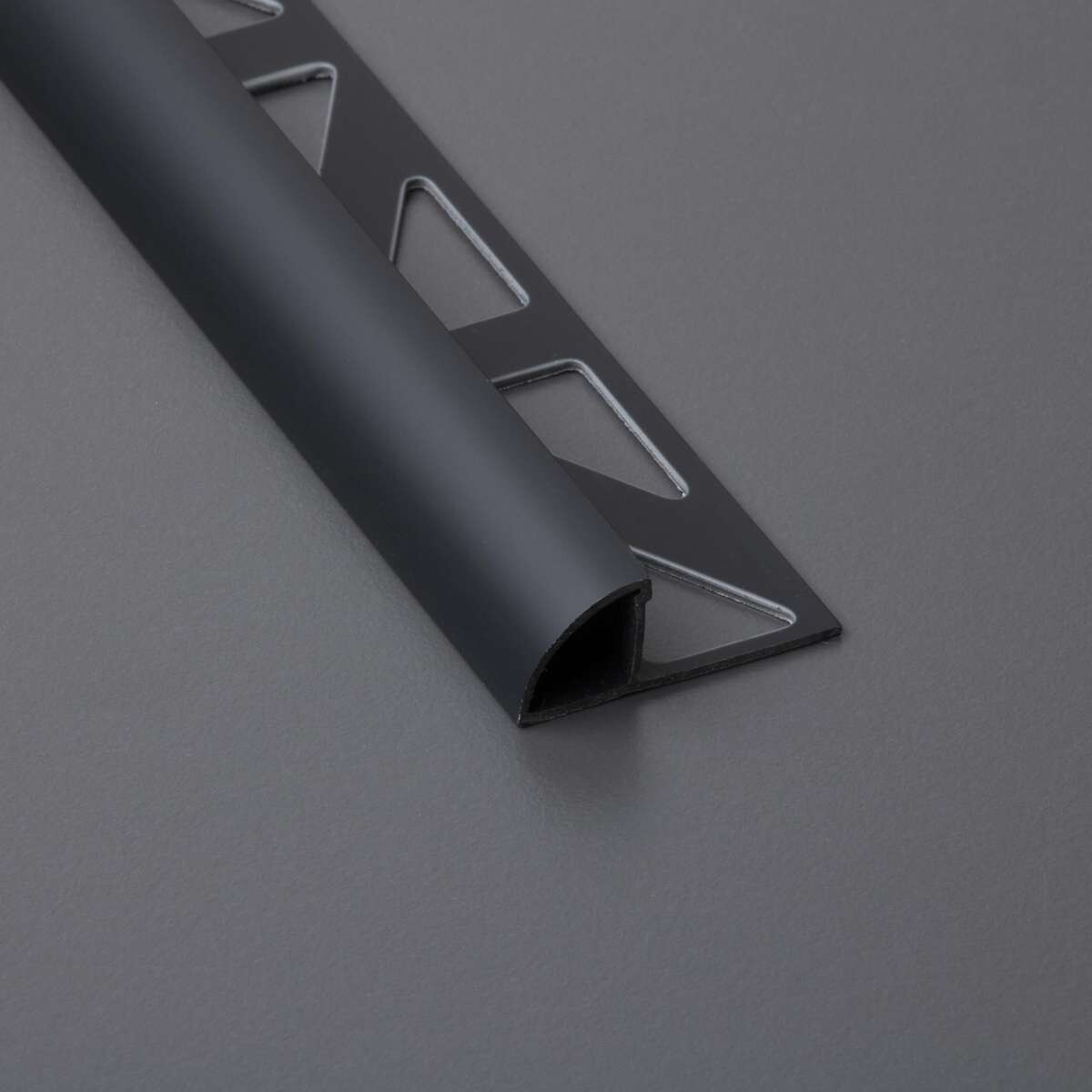 Nahaufnahme eines schwarzen Metallprofils mit rechteckigen Ausschnitten und gebogener Rand