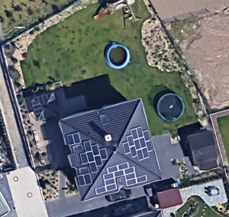 Luftaufnahme eines Hauses mit Solarmodulen, Garten mit zwei runden blauen Pools.