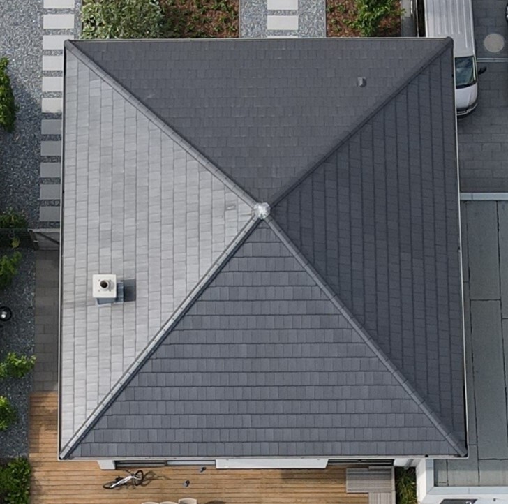 Vogelperspektive: Dach mit hellgrauer und dunkelgrauer Fläche, X-Form in Mitte; Holzterrasse vorne.